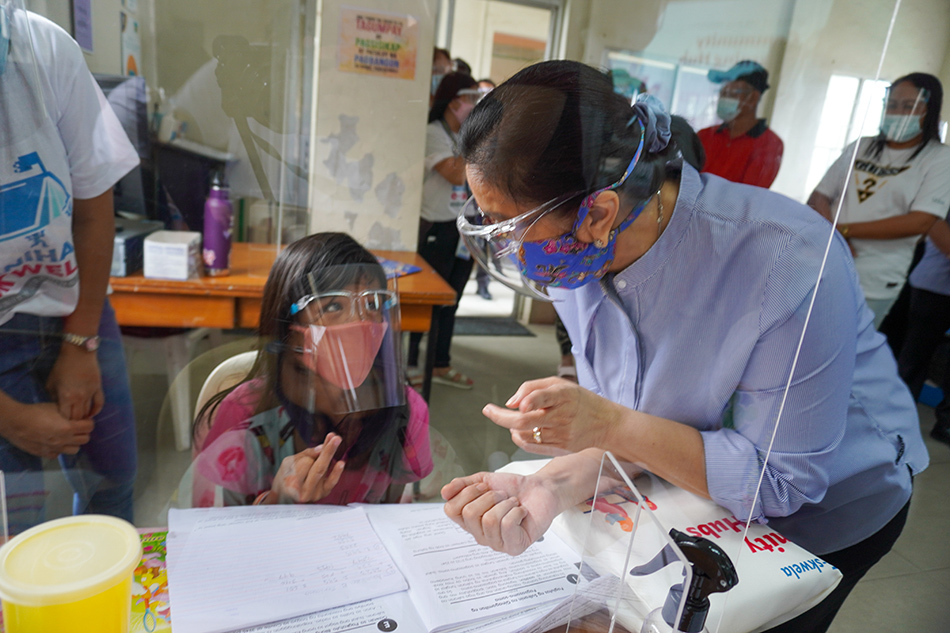 Tinutulungan ni Vice President Leni Robredo ang isang bata sa Community Learning Hub ng kaniyang tanggapan sa Taytay, Rizal noong Oktubre 2020. 