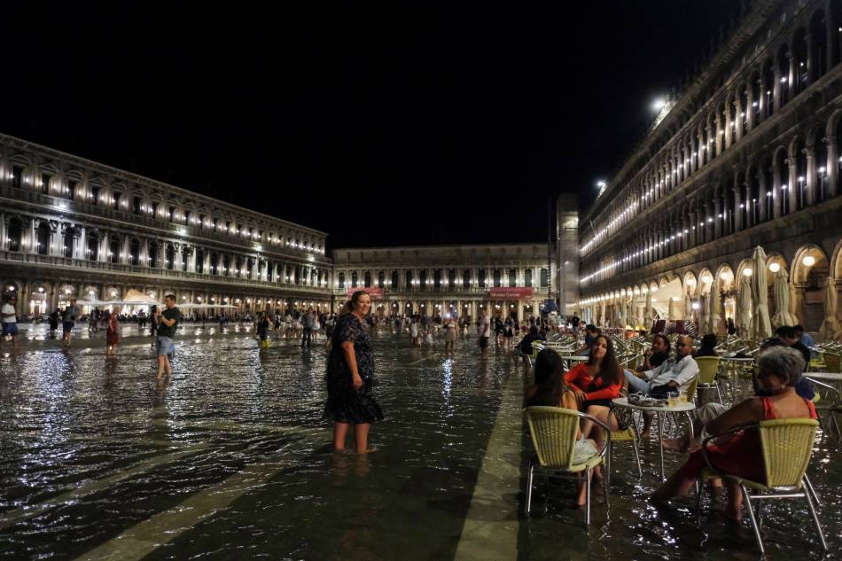 People sit at a cafe in a flooded St. Mark
