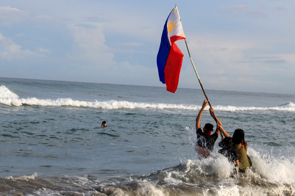 Filipino youth activists brave the waves as they hoist a Philippine flag on the shores of Zambales facing the West Philippine Sea as a symbol of the country’s to the disputed territory, June 12, 2017. Jun Dumaguing, ABS-CBN News/File