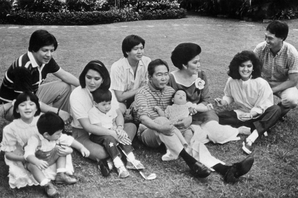 The late dictator Ferdinand Marcos (center) poses with members of his family on January 15, 1986, namely: his wife Imelda; eldest daughter Imee and her husband at the time, Tomas Manotoc (right); youngest daughter Irene and her husband Greggy Araneta (left); son Bongbong (behind Marcos); and Marcos' grandchildren Luis (on his lap), Alfonso (Irene's lap) and Borgy (left), carried by Ferdinand and Imelda's adopted daughter, Aimee. Malacañang handout/AFP