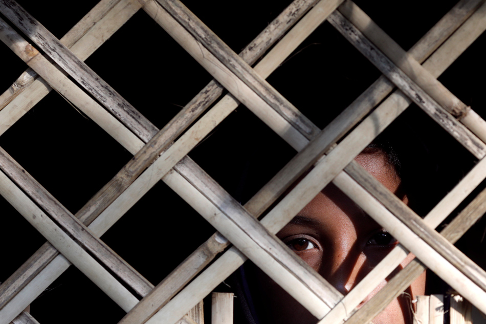 A Rohingya refugee child looks from inside a shelter at Kutupalong refugee camp near Cox's Bazar Bangladesh