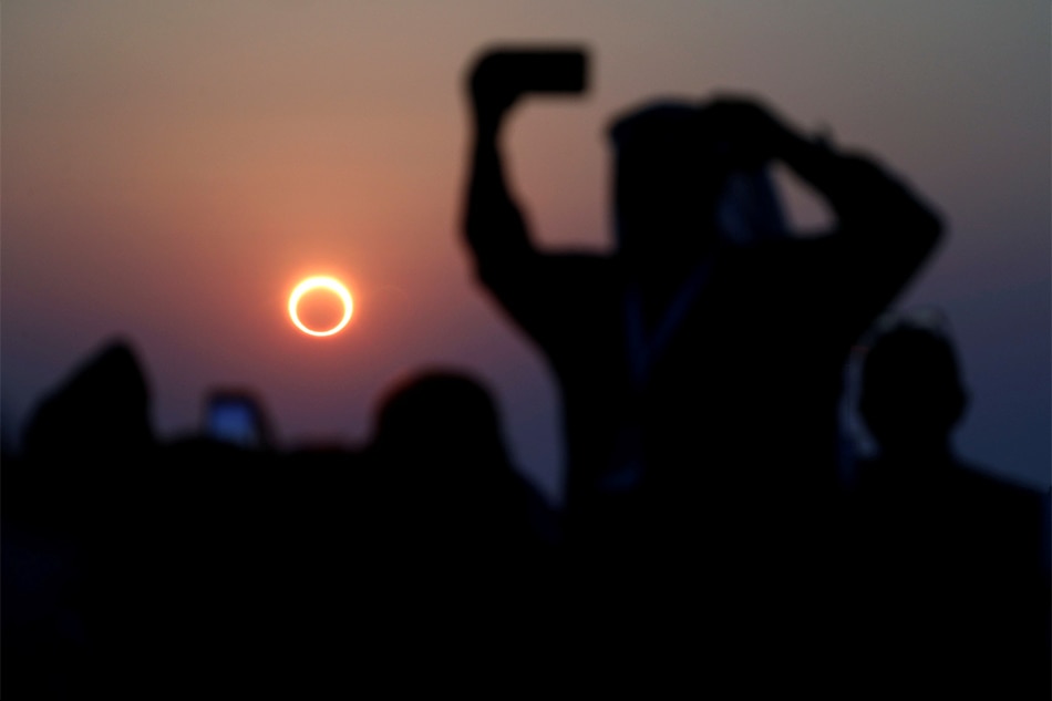 People take photos with their smartphones as they monitor the annular solar eclipse on Jabal Arba in Hofuf, in the Eastern Province of Saudi Arabia, Dec. 26, 2019