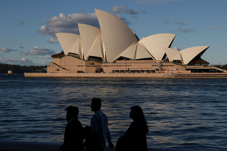 People stroll through a park in front of the Sydney Opera House amid easing of coronavirus disease (COVID-19) restrictions in Sydney, Australia, May 20, 2020. Loren Elliott, Reuters/File