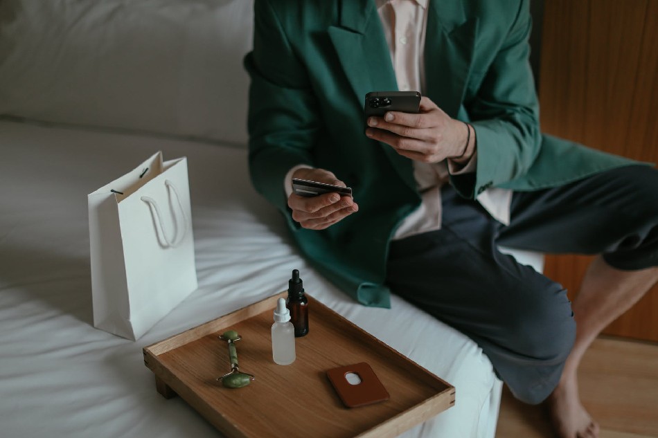 Photo source: Pexels [LINK OUT: https://www.pexels.com/photo/anonymous-man-using-smartphone-while-placing-order-with-credit-card-sitting-near-cosmetic-products-6634173/