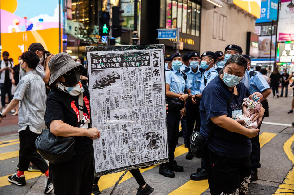 A woman (L) holds a front page copy of a newspaper from after China