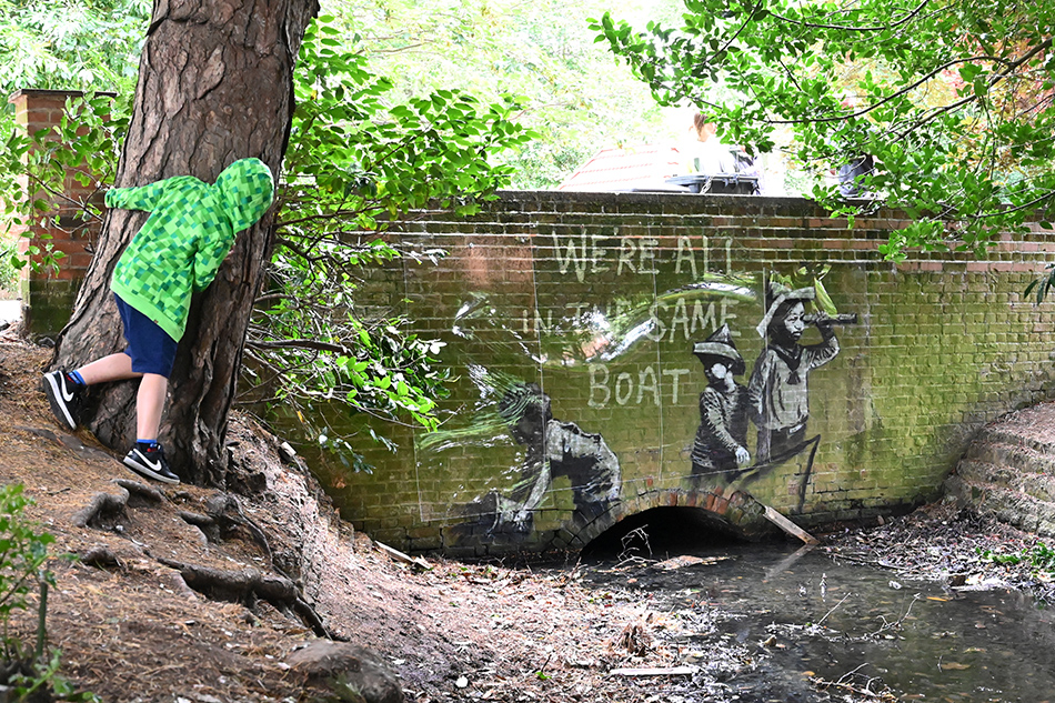In this photo taken on August 08, 2021, a stensil of children playing at being sailors is the subject of a graffiti artwork bearing the hallmarks of street artist Banksy on the wall of a bridge in Everitt Park in Lowestoft on the East coast of England. Banksy, Britain's most famous street artist, on August 13 confirmed what many had already suspected— that he is indeed the author of several works that have recently appeared in British seaside towns. An Instagram video clip just over three minutes long, and titled 