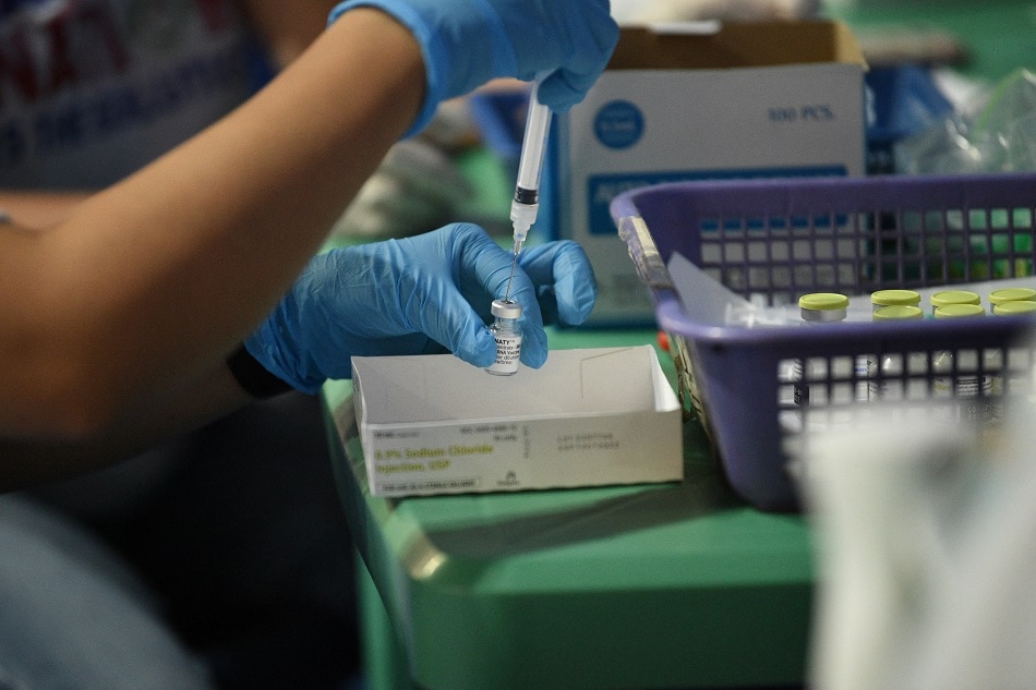 A health worker prepares a dose of the BioNtech Pfizer Covid-19 vaccine during a vaccination for seafarers at a stadium in Manila