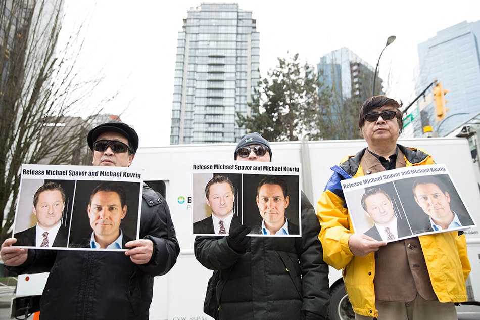 In this file photo taken on March 06, 2019, protesters hold photos of Canadians Michael Spavor and Michael Kovrig, who are being detained by China, outside the British Columbia Supreme Court, in Vancouver, as Huawei Chief Financial Officer Meng Wanzhou appears in court. Two Canadians imprisoned in what China's Western critics branded 