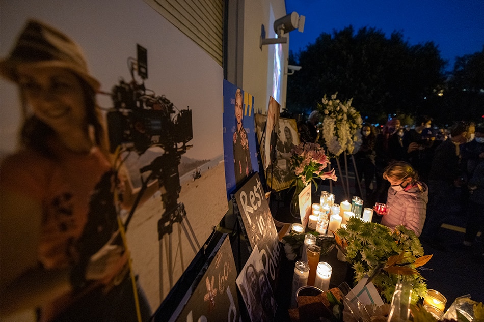 A girl pays respects near a photo of cinematographer Halyna Hutchins, who was accidentally killed by a prop gun fired by actor Alec Baldwin, at a memorial table during a candlelight vigil in her memory in Burbank, California on October 24, 2021. Police investigation on the shooting was focusing on the specialist in charge of the weapon and the assistant director who handed it to Baldwin. Ukraine-born cinematographer Halyna Hutchins, 42, was struck in the chest and died shortly after the incident Thursday in New Mexico, while director Joel Souza, 48, who was crouching behind her as they lined up a shot, was wounded and hospitalized, then released. David McNew, AFP