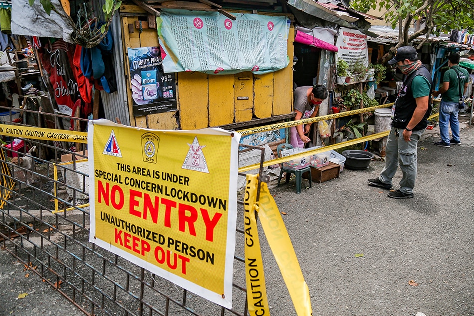 A woman sprays alcohol on the food pack she received from the city government in Barangay UP Campus, Quezon City on the first day of the re-implementation of the Enhanced Community Quarantine (ECQ) on August 6, 2021. George Calvelo, ABS-CBN News/File