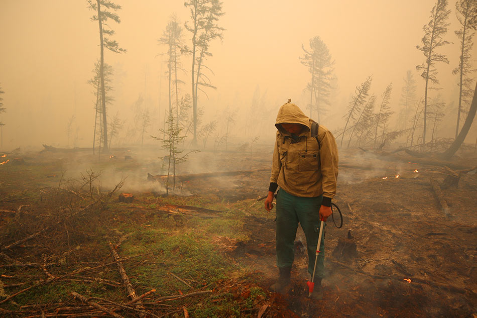 A specialist of the local forest protection service works to extinguish a forest fire near the village of Magaras in the region of Yakutia, Russia July 17, 2021. Roman Kutukov, Reuters/File