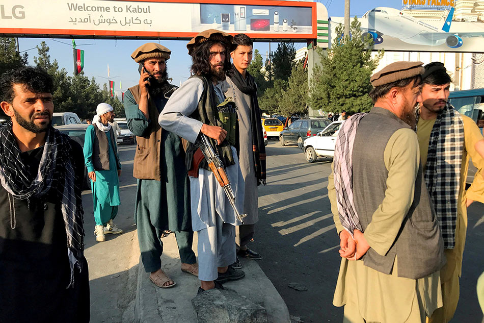 A member of Taliban (center) stands outside Hamid Karzai International Airport in Kabul, Afghanistan, August 16. Reuters stringer