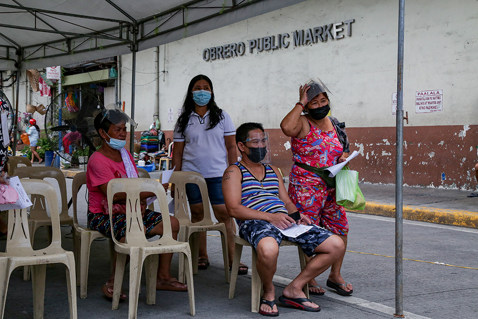People wait in line as the Manila Health Department inoculate market workers and vendors at the Blumentritt Market in Sta. Cruz, Manila on August 28, 2021. 