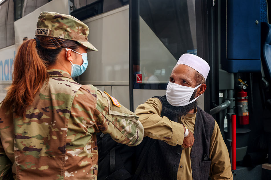 An Afghan refugee elbow bumps a US Army officer before boarding a bus that will take refugees to a processing center, upon arrival at Dulles International Airport in Dulles, Virginia, US, August 31, 2021. Evelyn Hockstein, Reuters