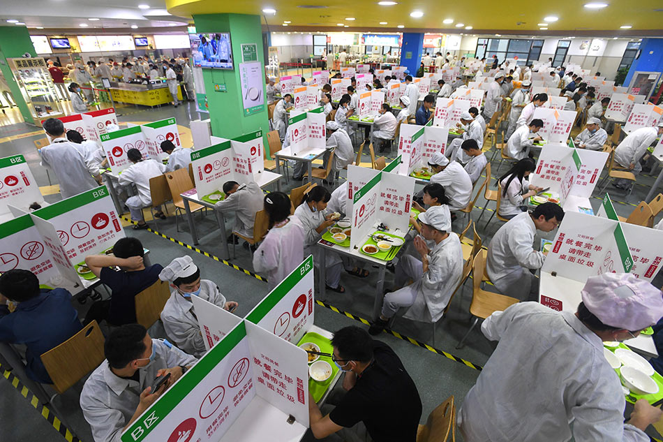 Employees dine at tables with partitions during dinner time at the canteen of a Lenovo factory following the coronavirus disease (COVID-19) outbreak in Wuhan, Hubei province, China August 13, 2021. Picture taken August 13, 2021. China Daily via REUTERS