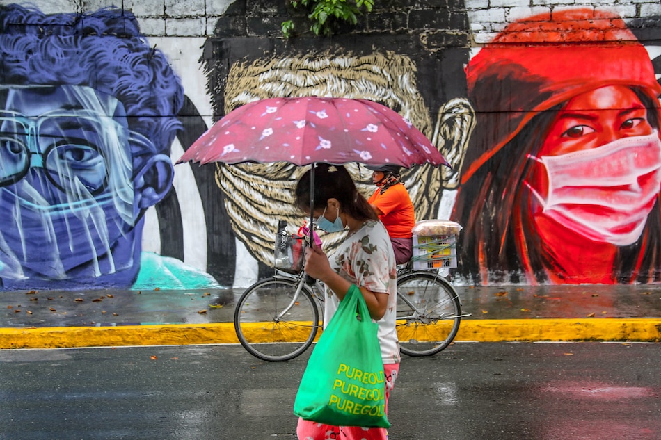 People pass by a mural by artists Sim Tolentino, Bryan Barrios and Moks featuring images of people during the COVID-19 pandemic painted on the walls of the Columban Missionaries building on Singalong Street in Manila on on Sept. 6, 2021. Jonathan Cellona, ABS-CBN News/File 