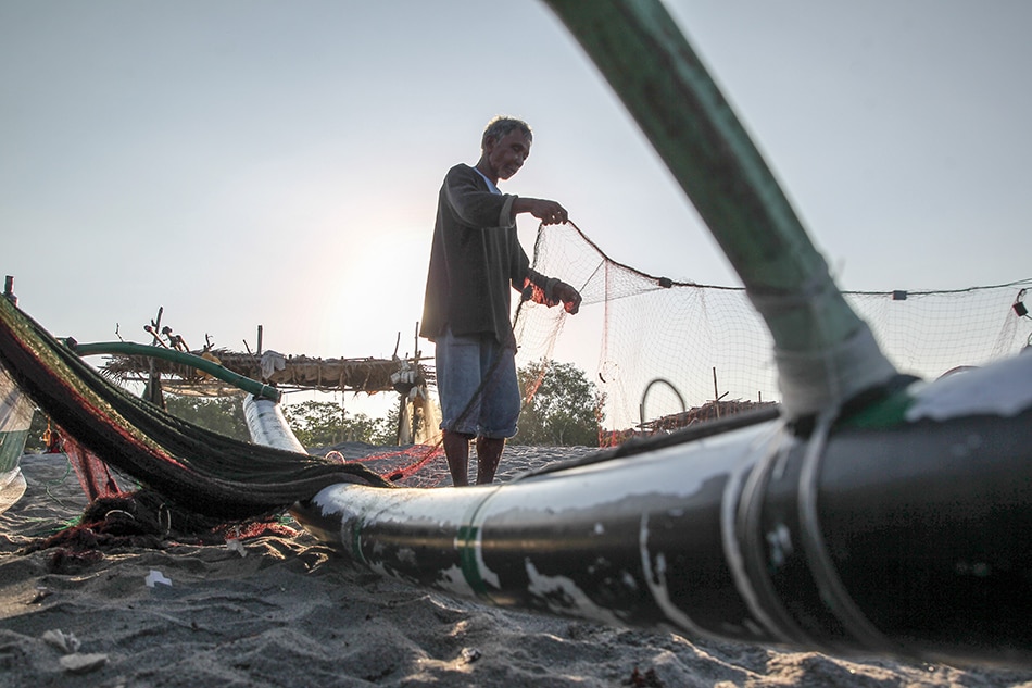 A fisherman mends his net after arriving from early morning fishing off the coast of Zambales on April 5, 2019. Jonathan Cellona, ABS-CBN News/file
