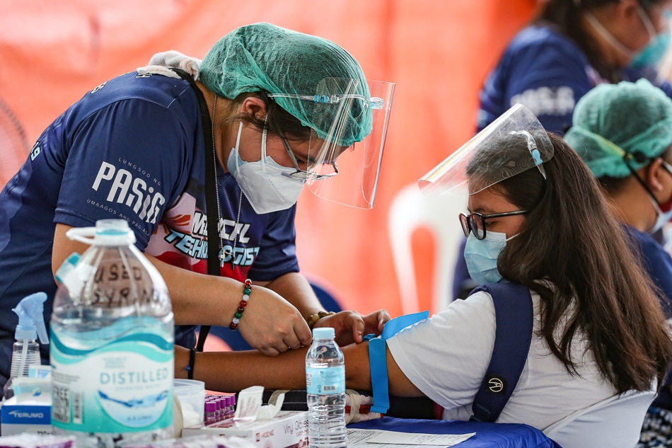 A medical technologist extracts samples from a patient at the San Joaquin Elementary School in Pasig City on July 2, 2021. As part of the city’s 448th anniversary, 500 teachers and non-teaching personnel are scheduled to receive Friday free annual physical exams which include laboratory tests, x-rays, and antigen swab tests. George Calvelo, ABS-CBN News