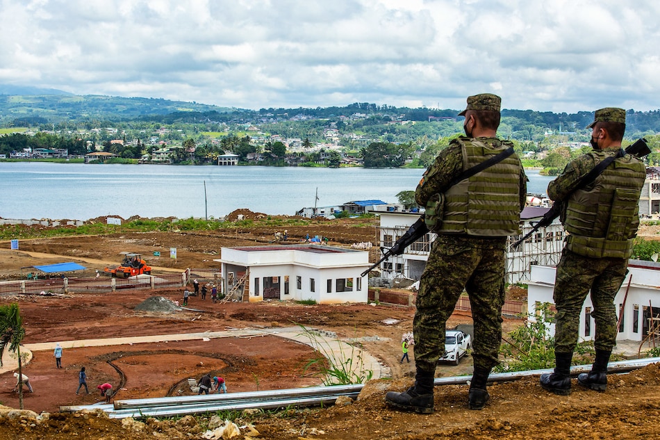 This photo taken on May 23, 2021 shows soldiers looking over workers constructing a building, which was a main battleground in 2017 when Islamic State-inspired Muslim militants laid siege to the southern Philippine city of Marawi, resulting in a 5-month campaign that claimed more than 1,000 lives until government troops re-took control. Ferdinandh Cabrera, AFP/File