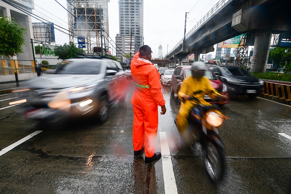 MMDA officers direct traffic along EDSA in Quezon City amid monsoon rainfall enhanced by Typhoon Fabian on July 22, 2021. Mark Demayo, ABS-CBN News
