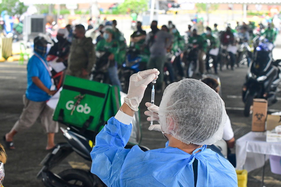 Delivery and transport workers queue up to receive a COVID-19 vaccine shot at the Vaccine Express, a drive-thru vaccination initiative under the Office of the Vice President, in a mall parking lot in Quezon City on August 12, 2021. 