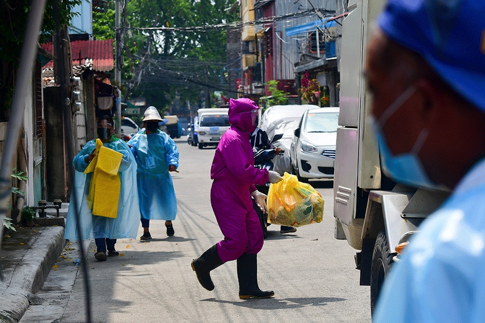 Volunteers assist garbage workers collecting trash from houses along a street in Brgy Commonwealth, Quezon City under 'special concern lockdown' on August 19, 2021. 