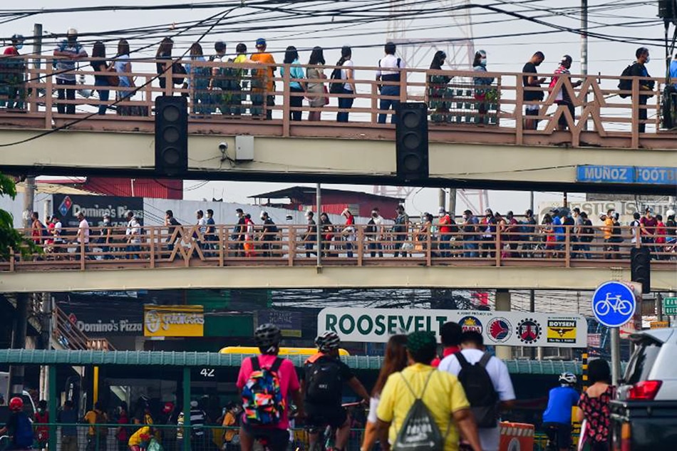 Commuters queue to ride the EDSA bus carousel from the Roosevelt station in Quezon City