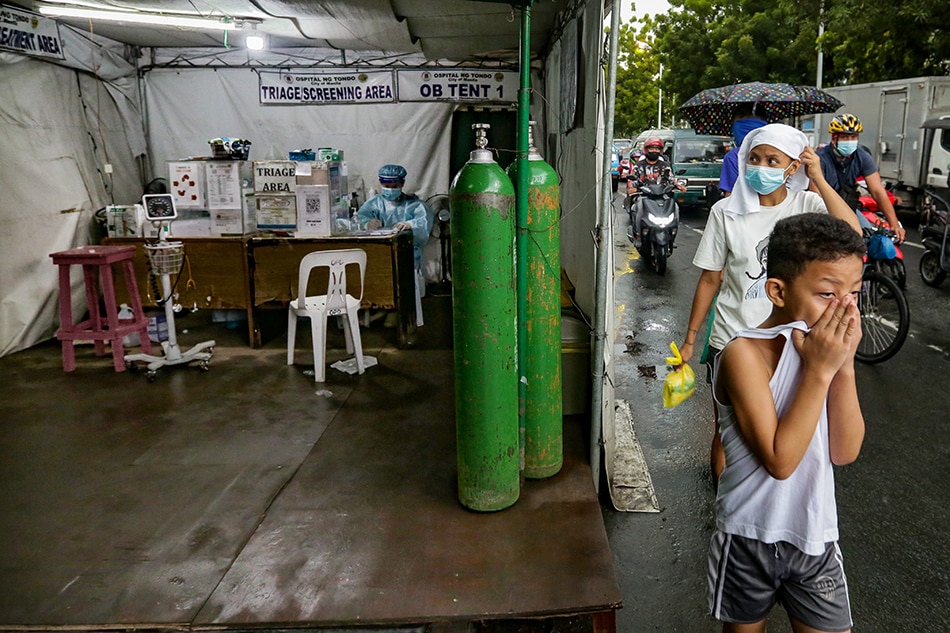 People pass beside the triage area of the Ospital ng Tondo located along Abad Santos avenue in Manila on August 25, 2021. 