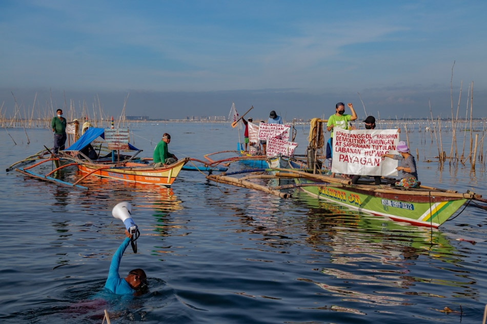 A man swims to pass on a megaphone to another boat as fisherfolk from the Samahan ng Mangingisda sa Parañaque (PANGISDA-Pilipinas) stage a fluvial protest at the Manila Bay on Tuesday. George Calvelo, ABS-CBN News