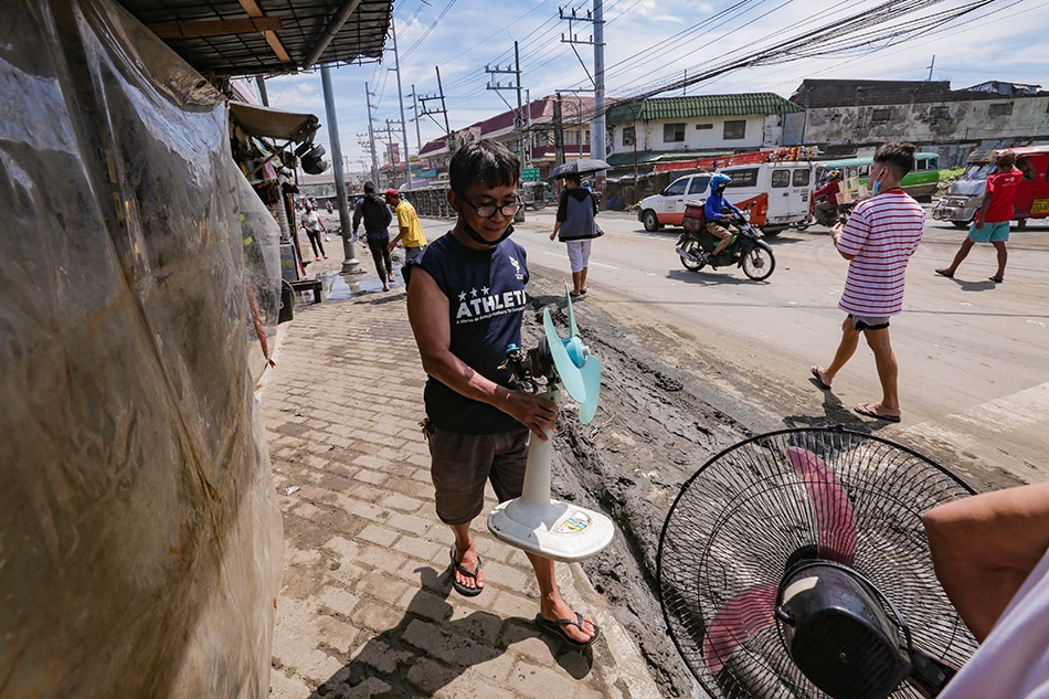 Pedestrians pass by as workers clear off mud along a main road in Las Piñas on Sept. 9, 2021. George Calvelo, ABS-CBN News/File 