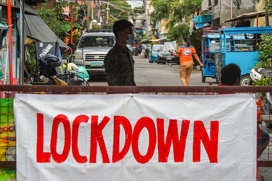 Barangay watchmen and police keep watch at an entry point to an alley under granular lockdown in Brgy 7 in Caloocan City on September 10, 2021.