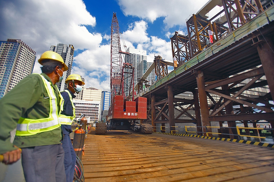 Two Chinese workers take a rest as authorities inspect the ongoing construction of the Binondo-Intramuros bridge in Manila on February 4, 2021. 