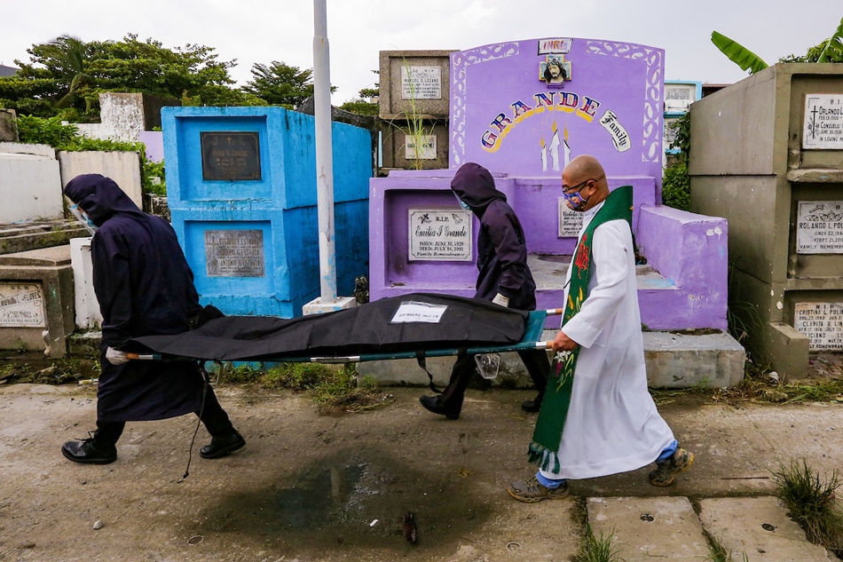 Fr. Flavie Villanueva along with workers carry the exhumed remains of Aljon Deparine at the Navotas Cemetery on Sept. 17, 2021. Deparine's mother said her son, then 22, was among boys picked up by masked men on motorbikes on Sept. 20, 2016. They were later found dead under a bridge. Several remains of alleged drug war victims were exhumed after the 5-year leases on their graves expired. George Calvelo, ABS-CBN News/File