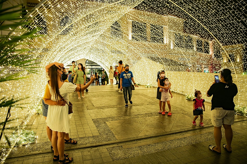 Mall-goers take pictures inside the Christmas lights tunnel during the ceremonial lighting of the gigantic floating Christmas tree at the Venice Grand Canal Mall in Taguig City on November 12, 2021. George Calvelo, ABS-CBN News