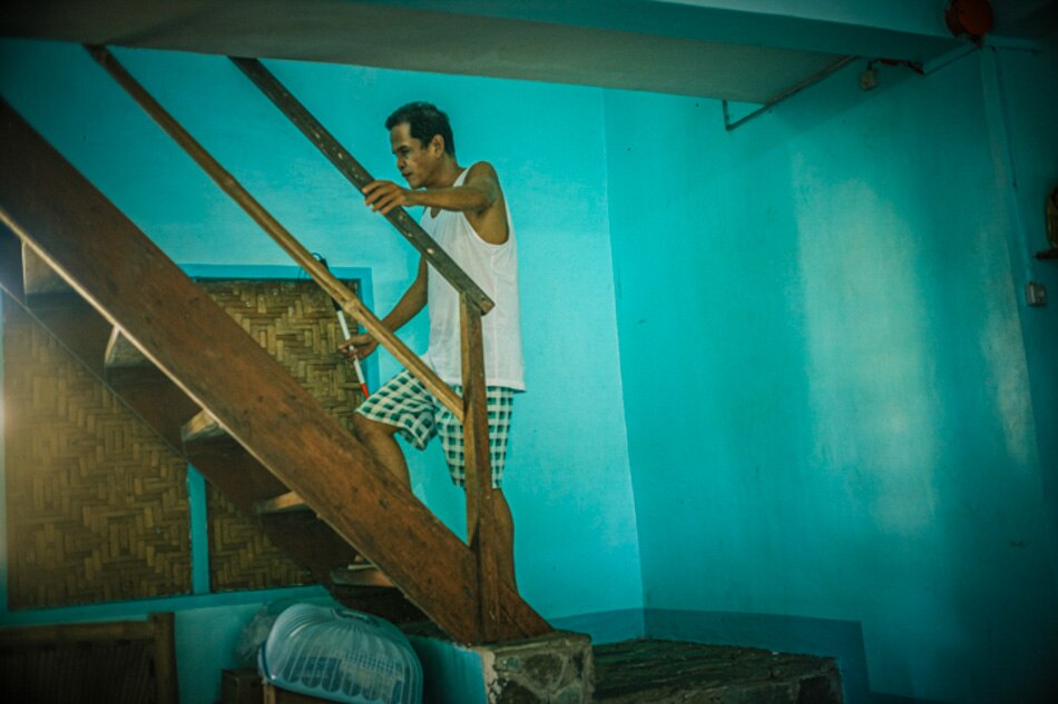 Nick Quieta climbs up to his room with the help of a blind man's cane. Since escaping near death caused by leptospirosis virus which attacked most of his vital organs, Nick has slowly adapted to his visual impairment with the help of his wife Chai. Photo by: Luis Liwanag