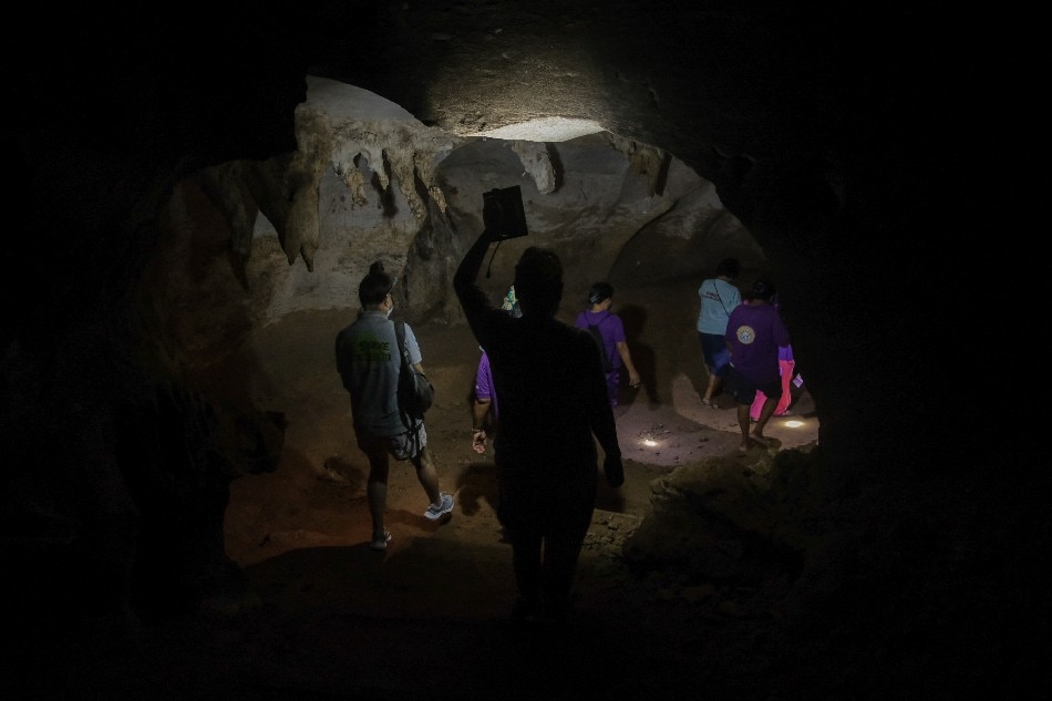 Women leave Tinabanan Cave in Marabut, Philippines, with the help of solar-powered flashlights, Oct 17, 2021. Geela Garcia, Thomson Reuters Foundation