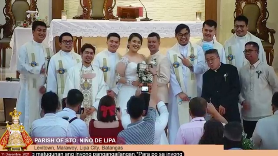  Priests take a group photo with the bride and groom in a screenshot of the live video of the wedding from the Parish of Sto. Nino de Lipa Facebook page