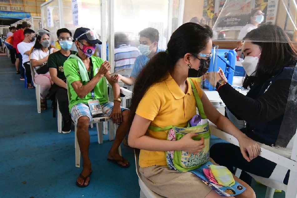 Quezon City residents receive their COVID-19 vaccine dose at the Batasan Hills National High School on November 29, 2021, the start of the 