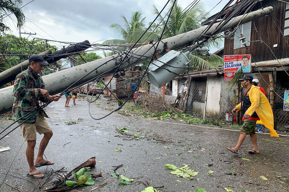 Village officials aid motorists in passing underneath an electric post topped by Typhoon Odette in Lapuz, Iloilo City on December 17, 2021. Kat Domingo, ABS-CBN News 