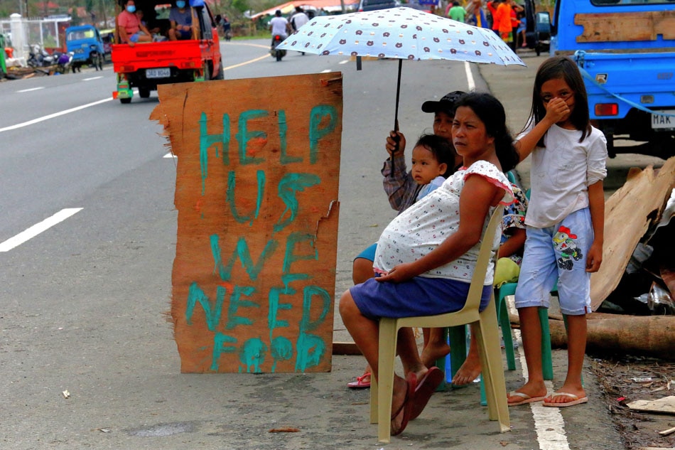A family displays signage as they seek alms along a highway in Surigao City, Surigao del Norte province on Christmas Day, more than a week after Super Typhoon Odette devastated the province. Ferdinand Cabrera, AFP