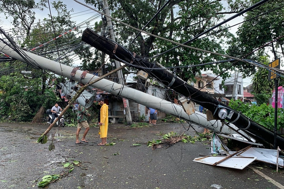 Village officials aid motorists in passing underneath an electric post topped by Typhoon Odette in Lapuz, Iloilo City on December 17, 2021. Kat Domingo, ABS-CBN News