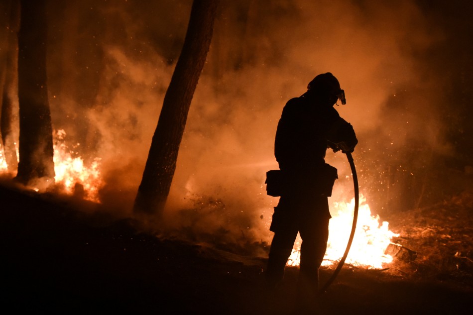 A firefighter battles a wildfire burning in the suburb of Thrakomakedones, north of Athens, Greece, August 7, 2021. Alexandros Avramidis, Reuters