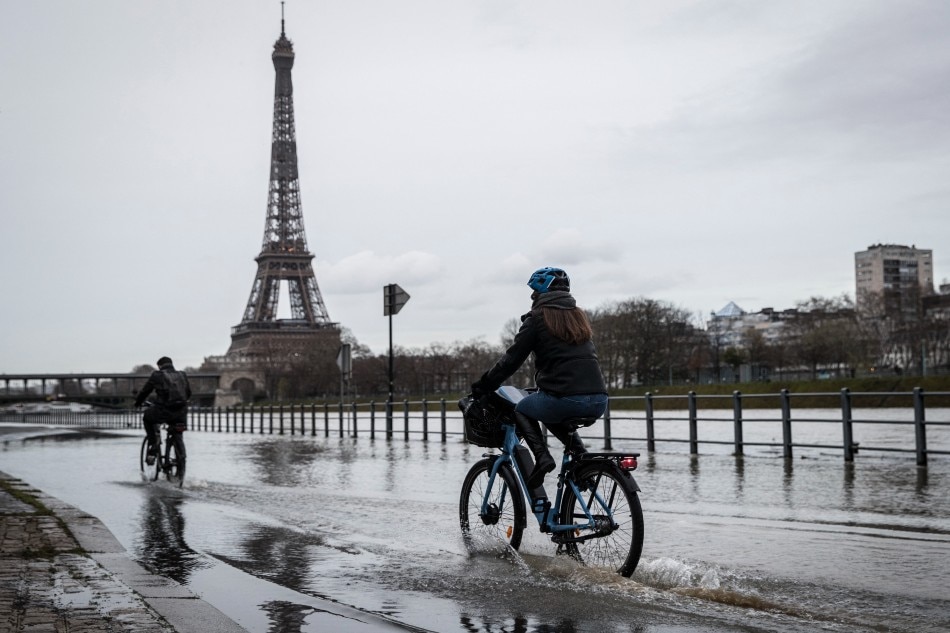 Cyclists ride on the flooded banks of the Seine river near the Eiffel Tower in Paris, on March 9, 2020. Thomas Samson, Agence France-Presse