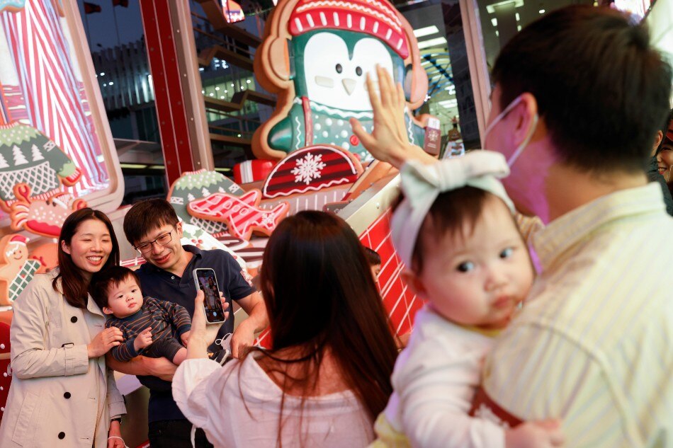 People pose in front of Christmas decorations outside Harbour City shopping mall in Hong Kong, China, November 18, 2021. Tyrone Siu, Reuters.