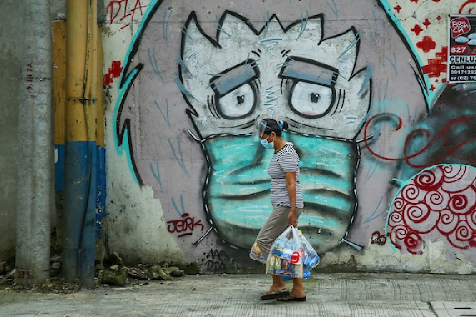 A person passes in front of a mural showing an image of a person wearing mask on 5th Avenue in Caloocan City on August 30, 2021. Jonathan Cellona, ABS-CBN News