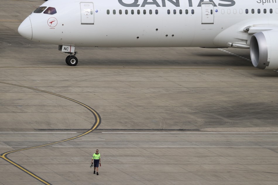 A ground worker walking near a Qantas plane is seen from the international terminal at Sydney Airport, as countries react to the new coronavirus Omicron variant amid the coronavirus disease (COVID-19) pandemic, in Sydney, Australia, on November 29, 2021. Loren Elliott, Reuters
