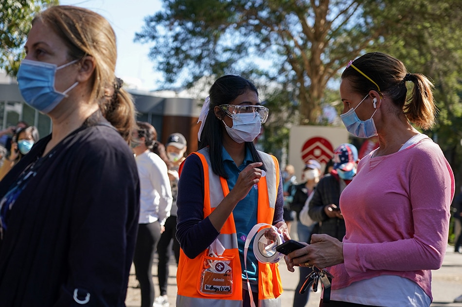 A staff member assists people waiting in line outside a coronavirus disease (COVID-19) vaccination center at Sydney Olympic Park during a lockdown to curb the spread of an outbreak in Sydney, Australia, August 16, 2021. Loren Elliott, Reuters