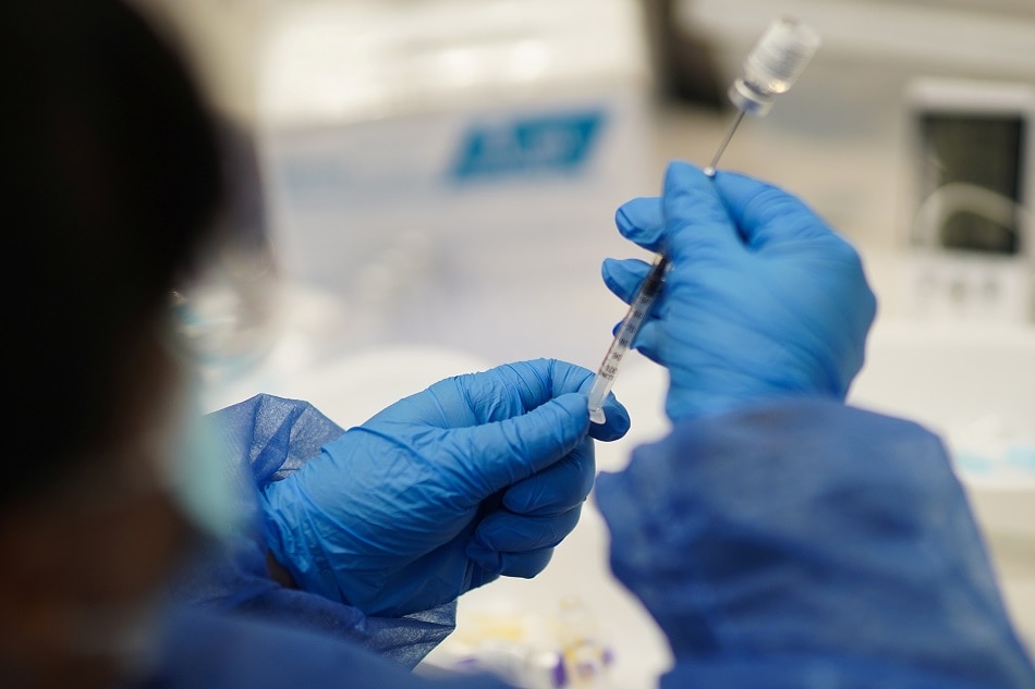 A health care worker prepares a dose of the Pfizer-BioNTech coronavirus disease (COVID-19) vaccine before being given to people who had previously been inoculated against the coronavirus disease (COVID-19) with Sinovac's Coronavac vaccine, in the Hospital de Clinicas, in Montevideo, Uruguay 