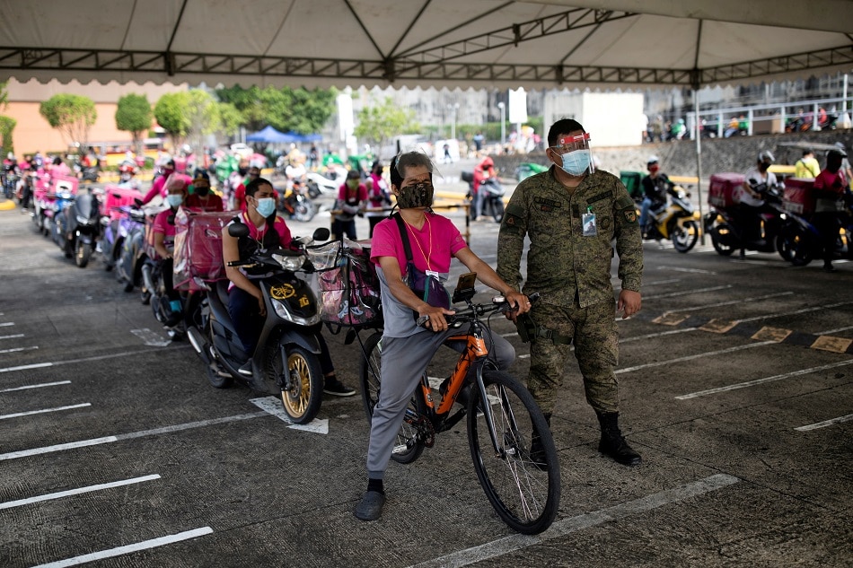 Service delivery riders queue to get vaccinated with Sinovac COVID-19 vaccine in a shopping mall's parking lot turned into a drive-thru vaccination site in Quezon City 
