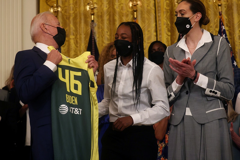 U.S. President Joe Biden jokes with Jewell Loyd and Breanna Stewart as he holds up a jersey he was gifted from members of the Seattle Storm 2020 WNBA Championship women’s basketball team at the White House in Washington, U.S., August 23, 2021. Leah Millis, Reuters